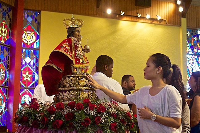 Girl praying in front of el santo nino de cebu