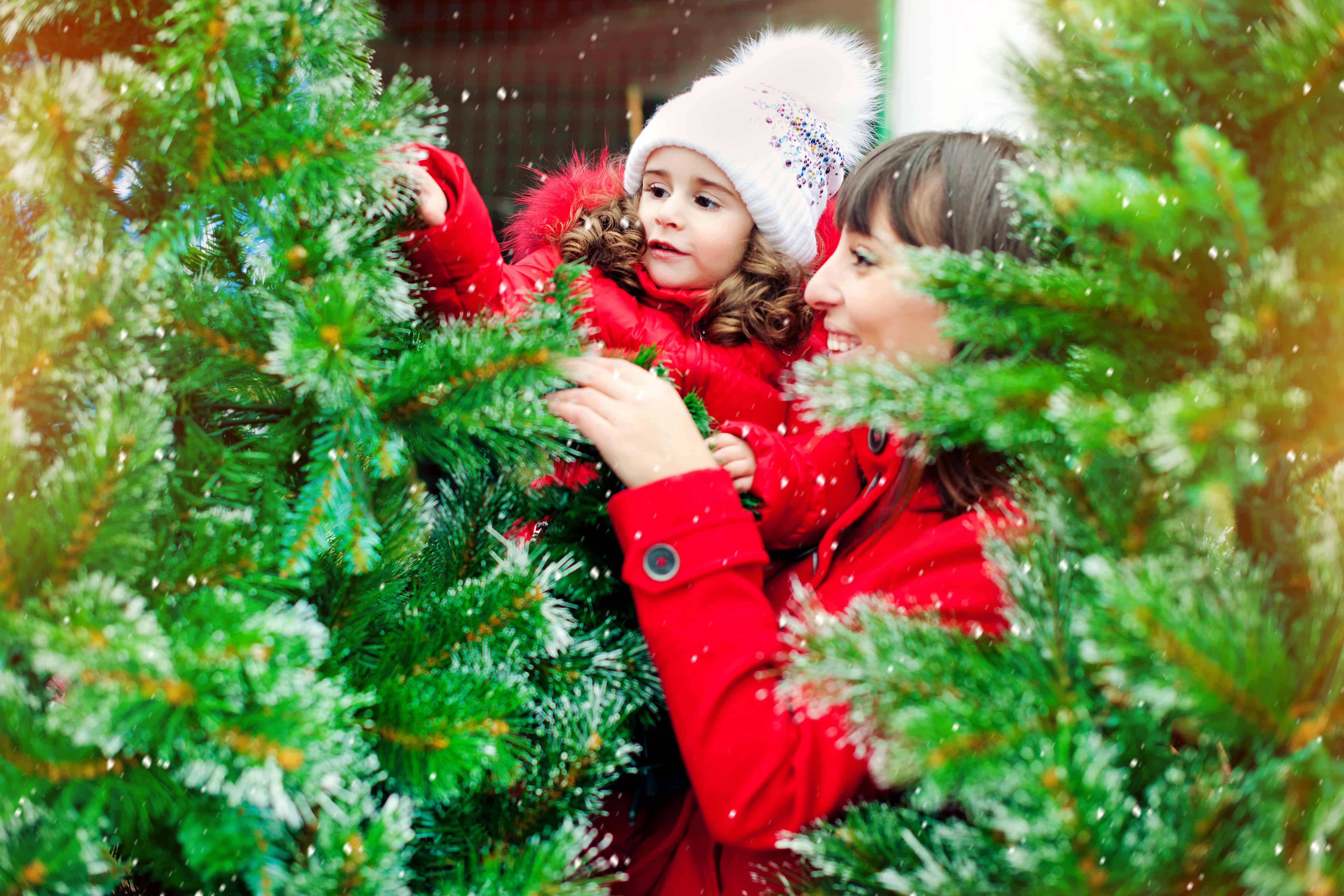 woman and child decorating a pine tree
